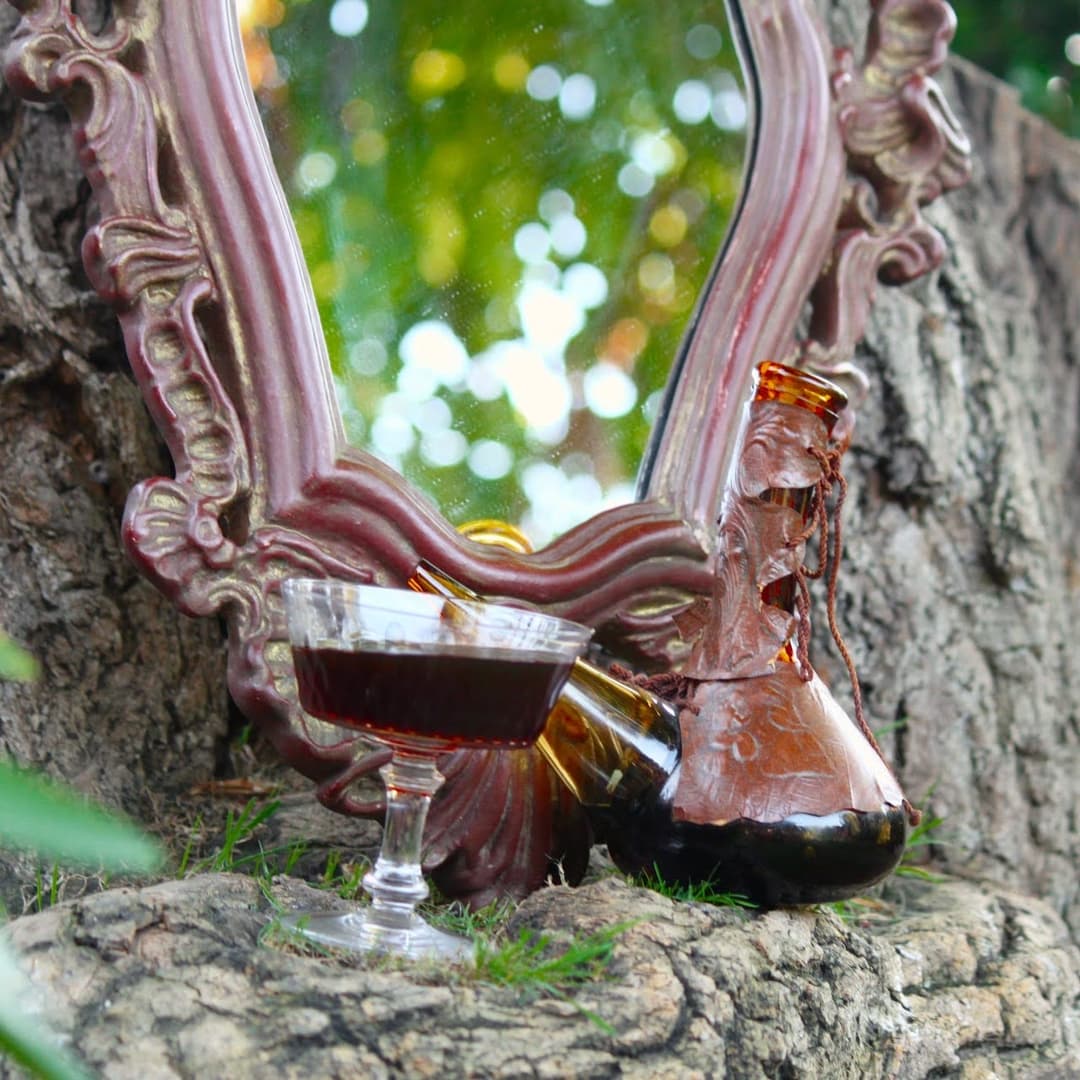 En un árbol, un espejo, una copa rellena de un elixir de color morado